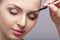 Beautiful woman blonde uses professional brush for eyebrow makeup.