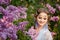 Beautiful woman in blooming lilac garden. Close up Portrait in sunset light