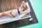 Beautiful woman in blue bikini lying on sun lounger by poolside