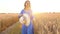 Beautiful woman in a blue dress and hat walking through a wheat field at sunset. Freedom concept. Wheat field in sunset
