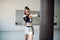 Beautiful woman boxing combat bag with sport trainer together. Girl boxer exercising box punch with personal coach.