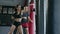 Beautiful woman boxing combat bag with sport trainer together. Girl boxer exercising box punch with personal coach.