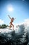 Beautiful woman in bright swimsuit jumps on the waves on surfboard.