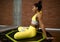 Beautiful woman in bright yellow tracksuit relaxes on trampoline in fitness studio