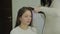 Beautiful woman with brown hair is having it treated with a curling iron by a hairdresser. Handheld real time