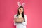 Beautiful woman in bunny ears headband holding basket with Easter eggs