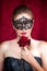 Beautiful woman in carnival mask with red rose