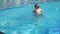 Beautiful woman catches little boy who jumping in pool. Slow motion.