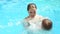 Beautiful woman catches little boy who jumping in pool. Slow motion.