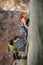 Beautiful woman climber climbing steep rock with rope