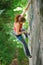 Beautiful woman climber climbing steep rock with rope