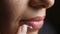 Beautiful woman close-up smears lips with cream