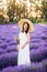 Beautiful woman collects lavender. A girl in a white sundress and hat in the summer in nature