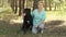 Beautiful woman in the coniferous summer forest with her beloved dog Cane Corso black