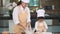 Beautiful woman and cute little Asian boy with eyeglasses, chef hat and apron playing and baking bakery in home kitchen funny. Hom