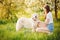 Beautiful woman cynologist playing with her dog Labrador retriever give paw in summer park