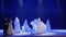 Beautiful woman dances with strangers in cloaks on the stage in theatre