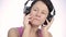 Beautiful woman dancing in headphones while listening to a music on a light background