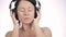 Beautiful woman dancing in headphones while listening to a music on a light background