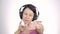 Beautiful woman dancing in headphones while listening to a music on a light background