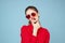 Beautiful woman in dark glasses red shirt bright makeup emotions attractive look blue background