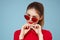 Beautiful woman in dark glasses red shirt bright makeup emotions attractive look blue background