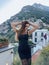 beautiful woman with dark hair in elegant clothes posing against the backdrop of the city Positano in Italy