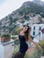 beautiful woman with dark hair in elegant clothes posing against the backdrop of the city Positano in Italy