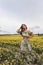 Beautiful woman with dark hair in elegant clothes posing in blooming rapeseed field