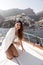 beautiful woman with dark hair in elegant clothes posing on the yacht against the backdrop of the city Positano