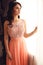 Beautiful woman with dark hair in elegant coral dress with diadem