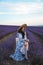 Beautiful  woman with dark hair in elegant dress with accessories posing in blooming lavender field