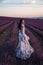 Beautiful  woman with dark hair in elegant dress with accessories posing in blooming lavender field