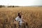 Beautiful  woman with dark hair in elegant dress with accessories posing in blooming wheat field