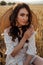 Beautiful  woman with dark hair in elegant dress with accessories posing in blooming wheat field