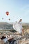 Beautiful woman with dark hair in elegant dress having picnic with fantastic view on valley with air balloons on background