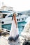 Beautiful woman with dark hair in elegant dress posing in dock with yachts