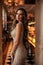 Beautiful woman with dark hair in elegant dress posing in elegant bakery cafe