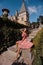 Beautiful woman with dark hair in elegant dress posing in park near antic castle