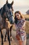 Beautiful woman with dark hair posing with horse in beautiful landscape