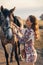 Beautiful woman with dark hair posing with horse in beautiful landscape