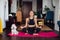 Beautiful woman doing exercise, practicing yoga, cute white puppy sits next to her owner, sporty girl wearing black