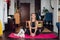 Beautiful woman doing exercise, practicing yoga, cute white puppy sits next to her owner, sporty girl wearing black