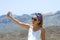 Beautiful woman doing a selfie on top of a mountain, with beautiful views of the vicinity of the teide behind her, looking