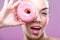 Beautiful woman with donuts, one eye than have a pink donut