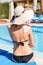 Beautiful woman with drawn sun by sun cream on her shoulder by the pool. Sun Protection Factor in vacation, concept