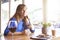 Beautiful woman drinking red wine with friends in sunny restaurant, portrait with wine glass near window. Vocation holidays bar