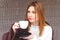 Beautiful woman drinks hot cofee from a white cup