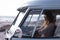 Beautiful woman driving camper van at beach on a sunny day