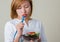 Beautiful woman eating salad with fork tape measure wrapped.